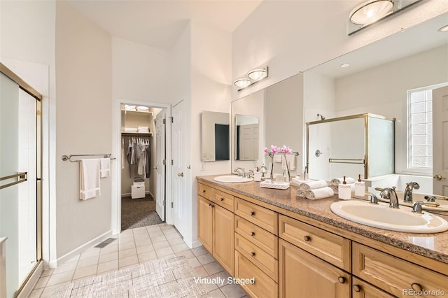 bathroom with double vanity, tile patterned flooring, a shower stall, and a sink