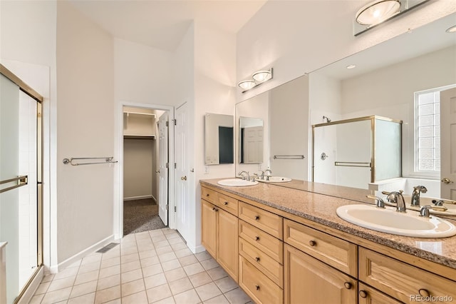 full bath featuring double vanity, tile patterned floors, a stall shower, and a sink