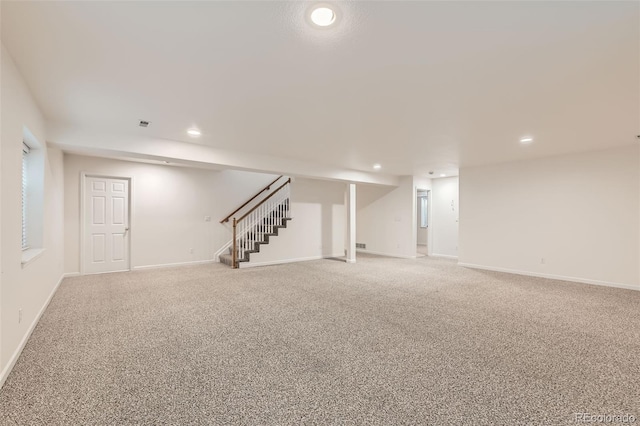 finished below grade area featuring light carpet, stairway, recessed lighting, and baseboards