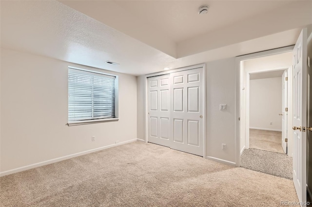 unfurnished bedroom featuring visible vents, a textured ceiling, baseboards, and carpet