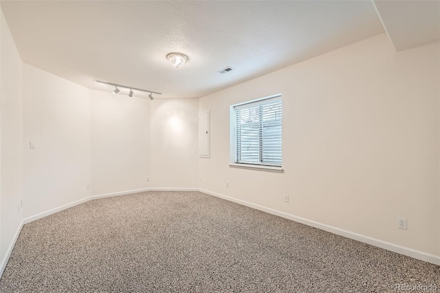 empty room featuring rail lighting, carpet flooring, baseboards, and visible vents