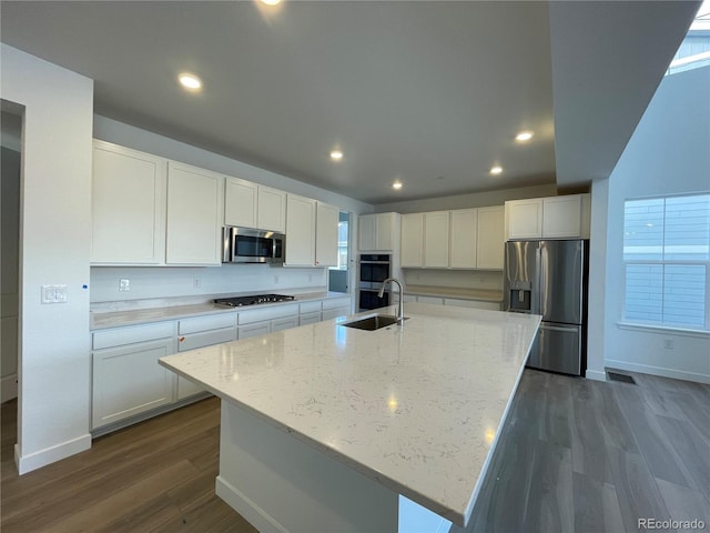 kitchen featuring light stone countertops, dark wood finished floors, white cabinets, stainless steel appliances, and a sink