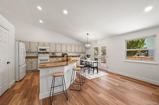 5554 S Ward Way, Littleton, CO 80127 - kitchen with white appliances, a sink, light wood-style floors, a kitchen breakfast bar, and a kitchen island with sink