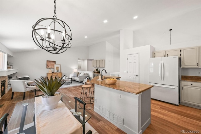 5554 S Ward Way, Littleton, CO 80127 - kitchen featuring freestanding refrigerator, open floor plan, light wood finished floors, a chandelier, and light stone countertops