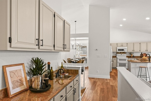 5554 S Ward Way, Littleton, CO 80127 - kitchen with white appliances, light wood finished floors, a chandelier, a sink, and baseboards