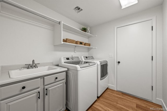 5554 S Ward Way, Littleton, CO 80127 - clothes washing area featuring independent washer and dryer, light wood finished floors, and cabinet space