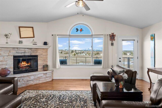 living room with wood finished floors, a fireplace, baseboards, ceiling fan, and vaulted ceiling