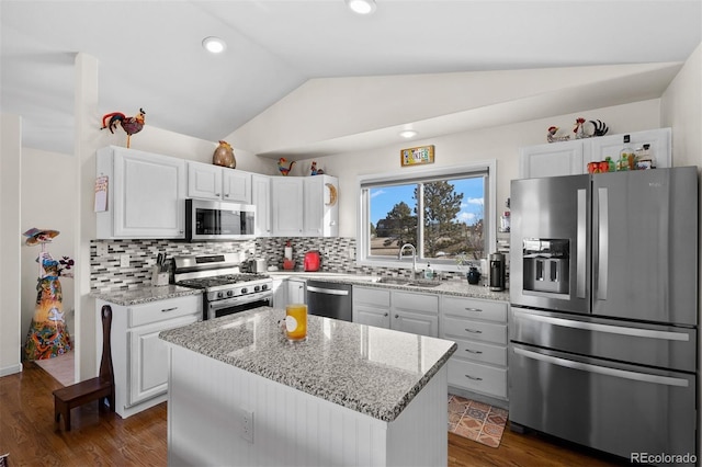 kitchen featuring tasteful backsplash, vaulted ceiling, appliances with stainless steel finishes, white cabinetry, and a sink