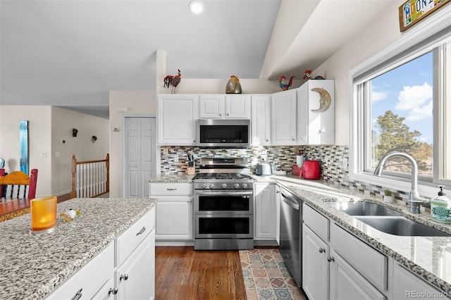 kitchen with dark wood finished floors, white cabinets, appliances with stainless steel finishes, and a sink