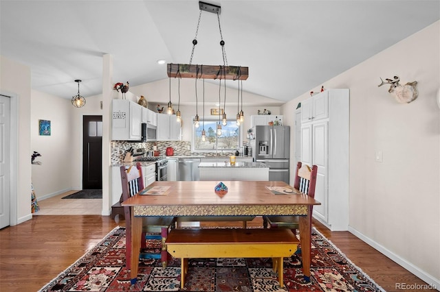 dining space with light wood-style flooring, baseboards, and vaulted ceiling