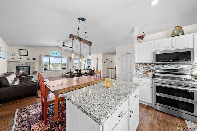 kitchen featuring ceiling fan, open floor plan, vaulted ceiling, appliances with stainless steel finishes, and wood finished floors