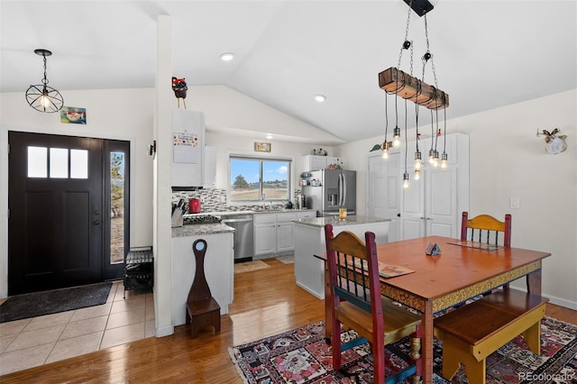 dining area with light wood-style floors and vaulted ceiling