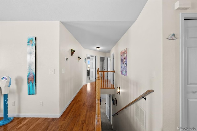 hallway featuring visible vents, an upstairs landing, baseboards, and wood finished floors