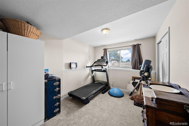 workout room with baseboards, carpet floors, and a textured ceiling