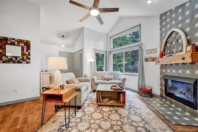 11820 W 66th Pl Unit C, Arvada, CO 80004 - living room featuring wood finished floors, a tile fireplace, ceiling fan, high vaulted ceiling, and baseboards