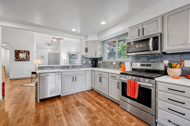 11820 W 66th Pl Unit C, Arvada, CO 80004 - kitchen with stainless steel appliances, a sink, decorative backsplash, light countertops, and light wood-style floors