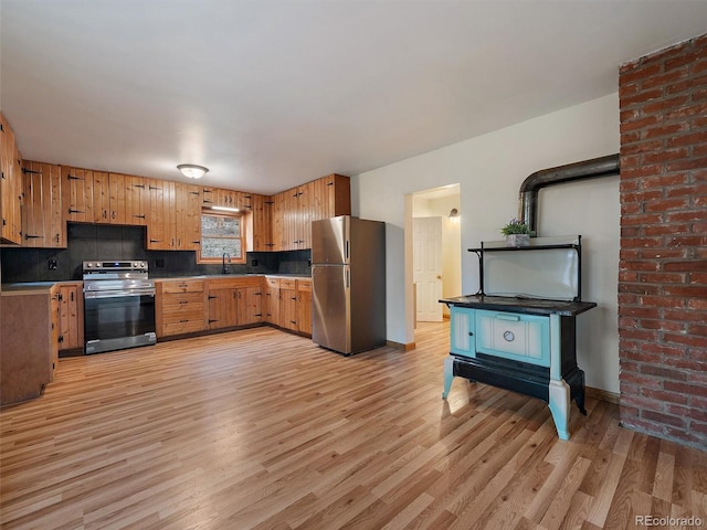 kitchen featuring light wood-type flooring, stainless steel appliances, and tasteful backsplash