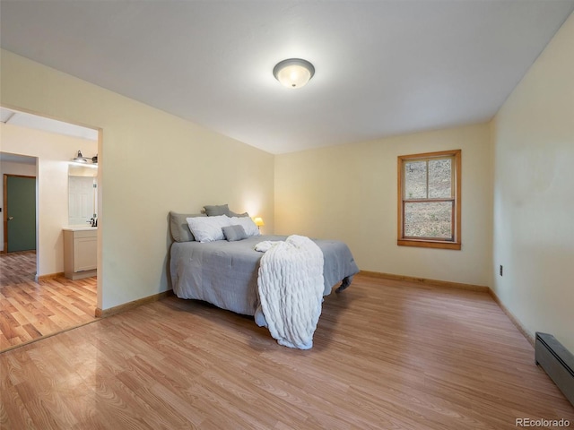 bedroom featuring baseboard heating, ensuite bath, and light hardwood / wood-style floors