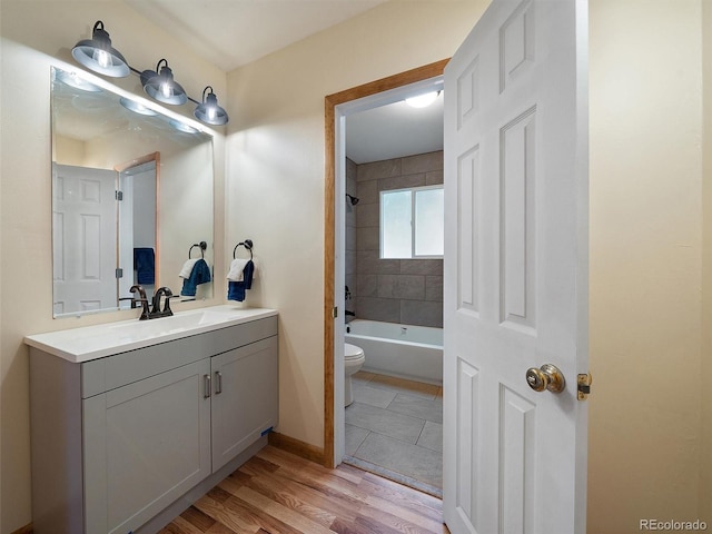 full bathroom featuring hardwood / wood-style flooring, vanity, toilet, and tiled shower / bath