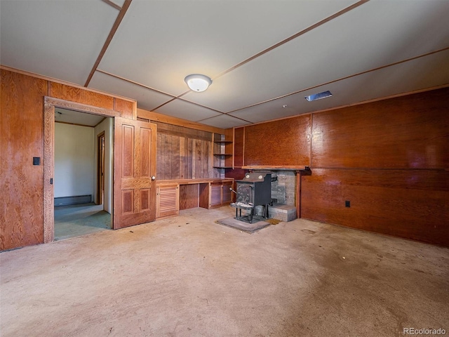 unfurnished living room with a wood stove and wood walls