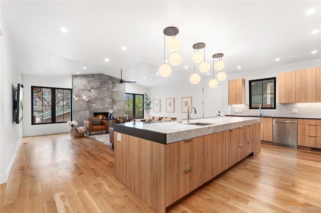 1675 S Steele St, Denver, CO 80210 - kitchen featuring modern cabinets, dishwasher, a large island with sink, a tiled fireplace, and light wood-style floors