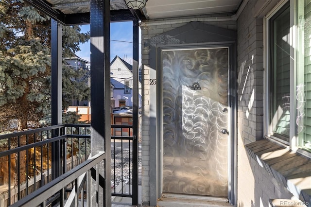 doorway to property with brick siding and a balcony