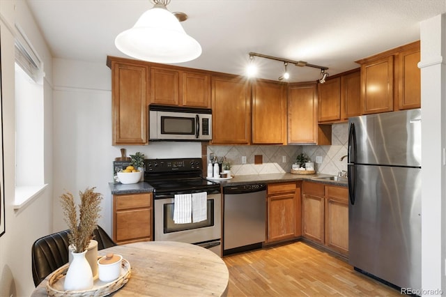 kitchen featuring decorative light fixtures, appliances with stainless steel finishes, light hardwood / wood-style flooring, and tasteful backsplash