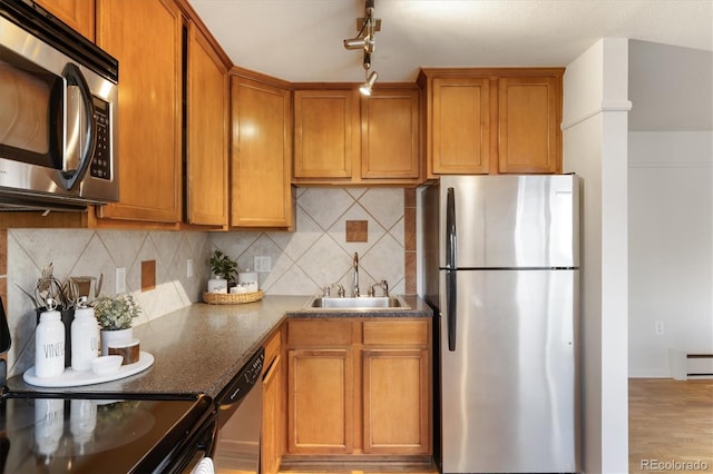 kitchen featuring backsplash, stainless steel appliances, sink, light hardwood / wood-style flooring, and a baseboard radiator