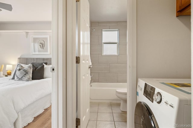 bathroom featuring washer / dryer, tile patterned floors, toilet, and tiled shower / bath