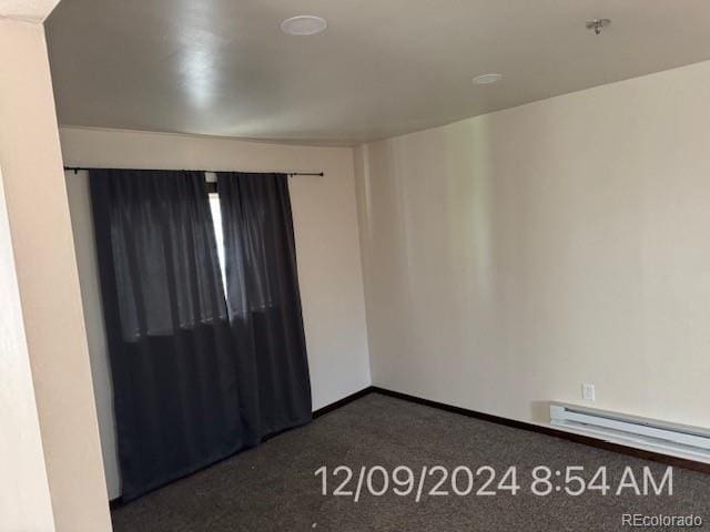 carpeted spare room featuring a baseboard heating unit