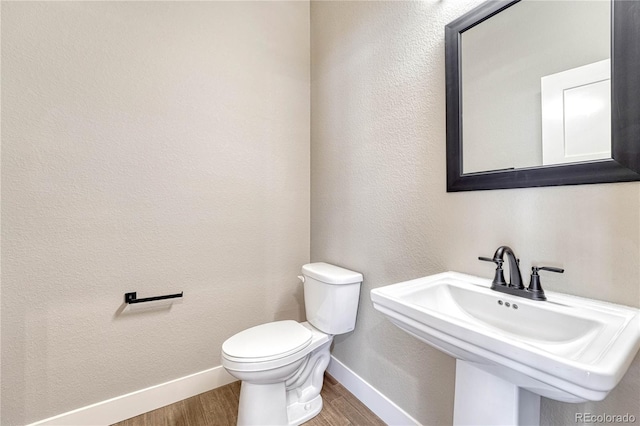 bathroom with wood-type flooring, toilet, and sink