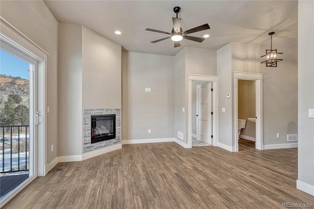 unfurnished living room with hardwood / wood-style floors, a stone fireplace, and ceiling fan