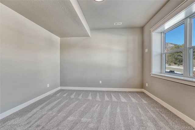 carpeted empty room featuring a textured ceiling