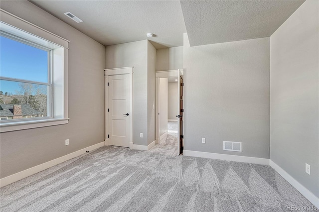 unfurnished bedroom featuring light carpet and a textured ceiling