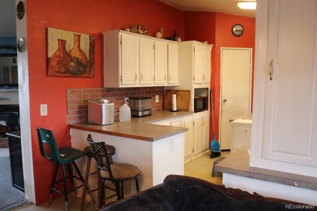 kitchen featuring backsplash, white cabinetry, and a kitchen breakfast bar