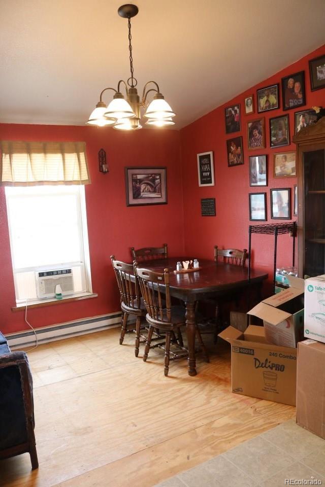 dining area with a baseboard radiator, hardwood / wood-style flooring, an inviting chandelier, cooling unit, and lofted ceiling