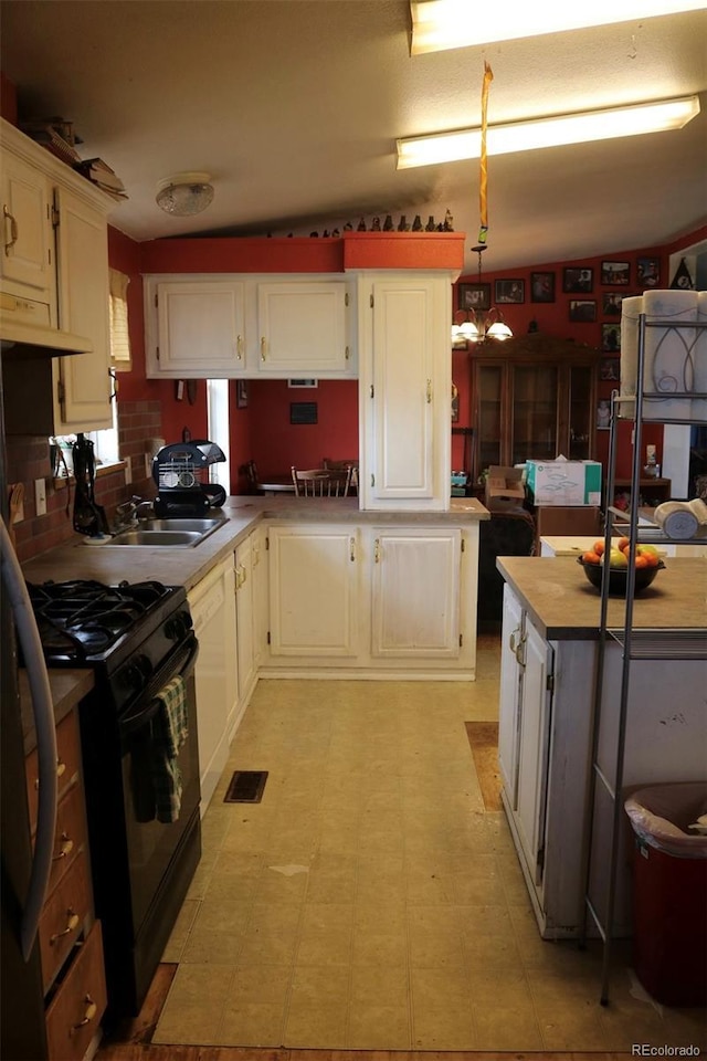 kitchen featuring white cabinetry, sink, pendant lighting, and black range with gas stovetop