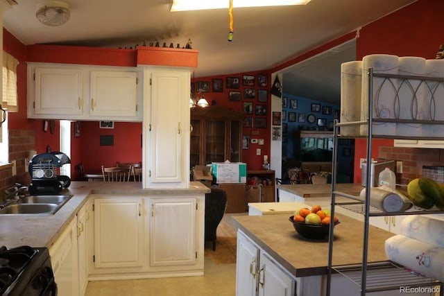 kitchen with sink, white cabinets, black range with gas cooktop, and lofted ceiling