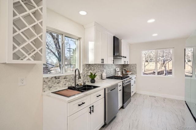 kitchen with decorative backsplash, sink, stainless steel appliances, white cabinets, and wall chimney exhaust hood