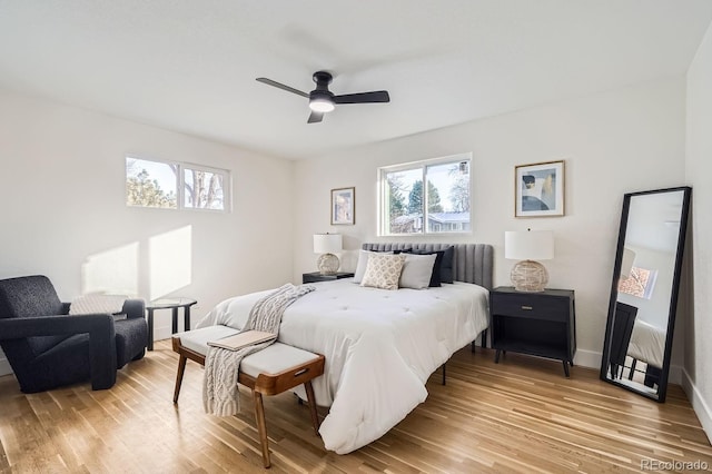 bedroom featuring ceiling fan, hardwood / wood-style flooring, and multiple windows