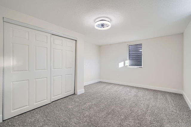 unfurnished bedroom featuring a textured ceiling, a closet, and carpet flooring