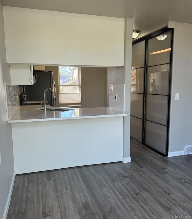 kitchen featuring white cabinetry, dark wood-type flooring, a sink, and light countertops