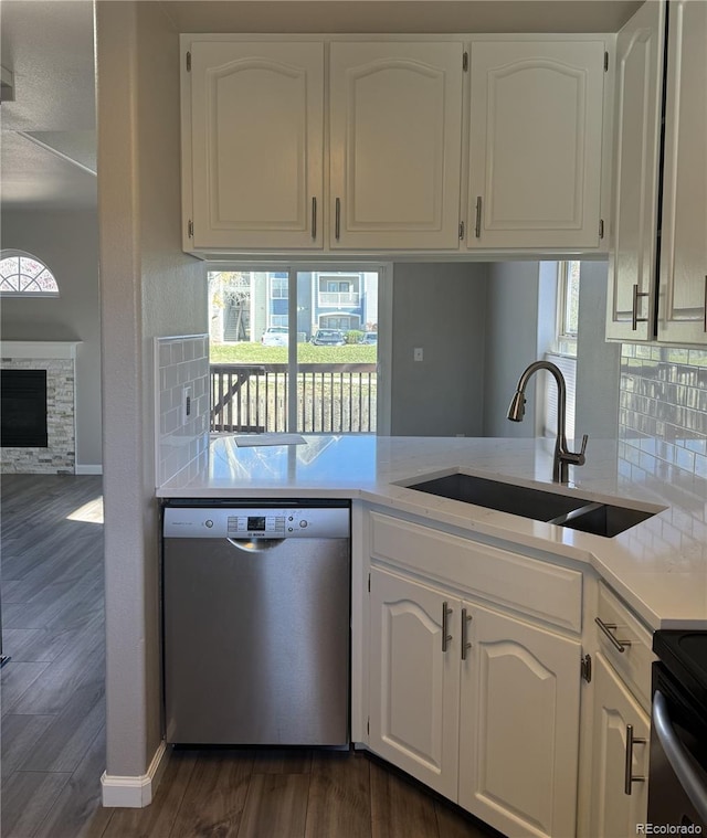 kitchen with a sink, dark wood finished floors, light countertops, and stainless steel dishwasher