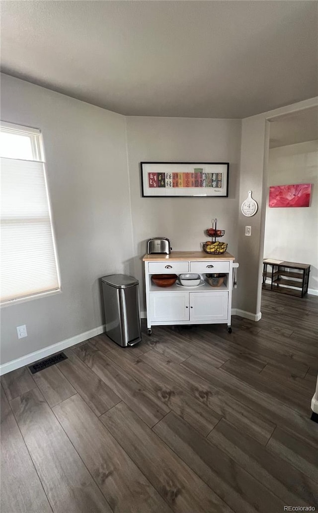 bar featuring dark wood finished floors, visible vents, and baseboards