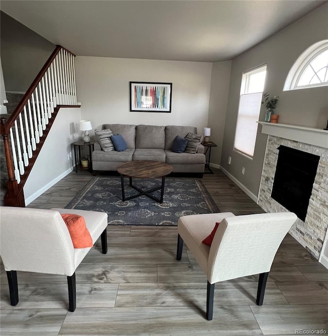 living room featuring stairway, a fireplace, wood finished floors, and baseboards