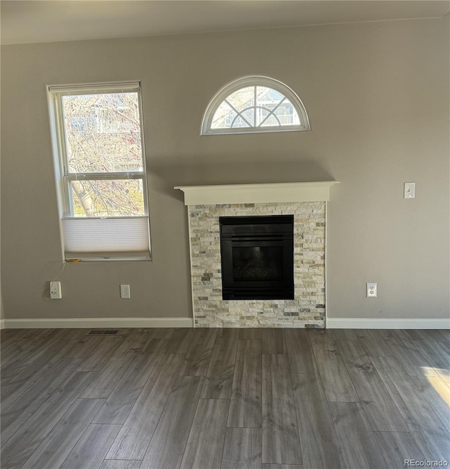 unfurnished living room featuring baseboards, a wealth of natural light, and wood finished floors