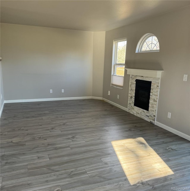 unfurnished living room featuring a fireplace, wood finished floors, and baseboards