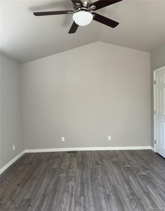 empty room featuring dark wood-style floors, lofted ceiling, visible vents, a ceiling fan, and baseboards