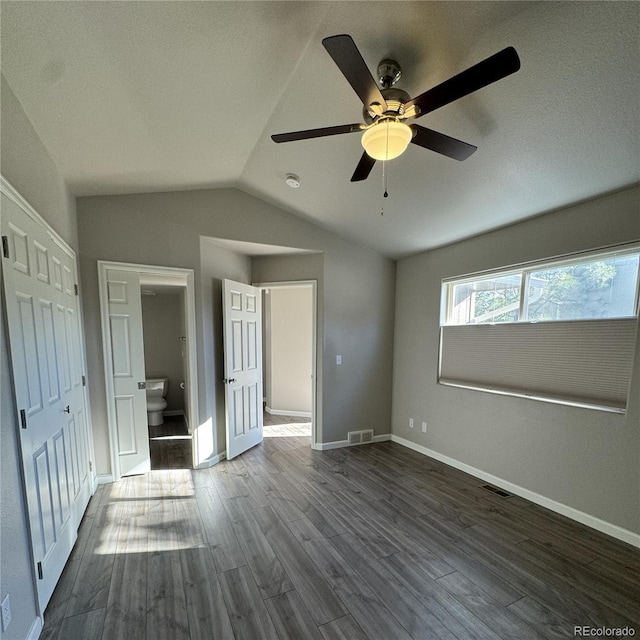 unfurnished bedroom featuring dark wood-type flooring, visible vents, vaulted ceiling, and baseboards