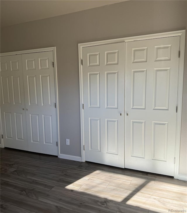 unfurnished bedroom featuring a closet, wood finished floors, and baseboards